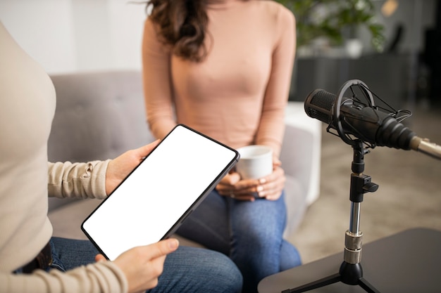 Mujeres haciendo radio junto con micrófono y tableta.