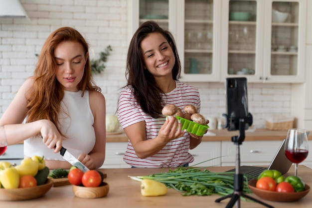 Foto gratuita mujeres haciendo un vlog mientras preparan comida