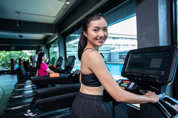 Mujeres hermosas fitness preparan para correr en la cinta en el gimnasio.