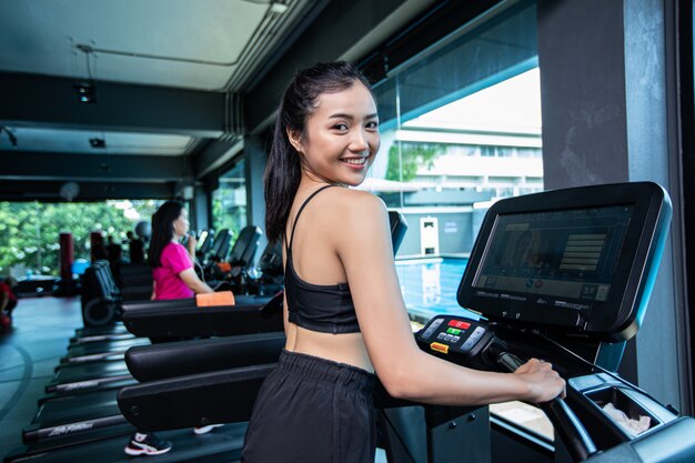 Mujeres hermosas fitness preparan para correr en la cinta en el gimnasio.