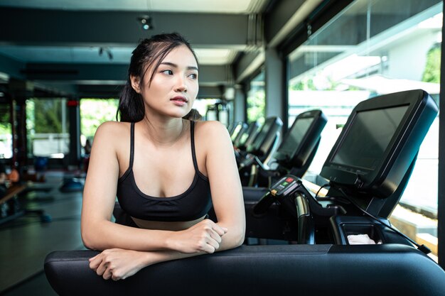 Mujeres hermosas fitness preparan para correr en la cinta en el gimnasio.