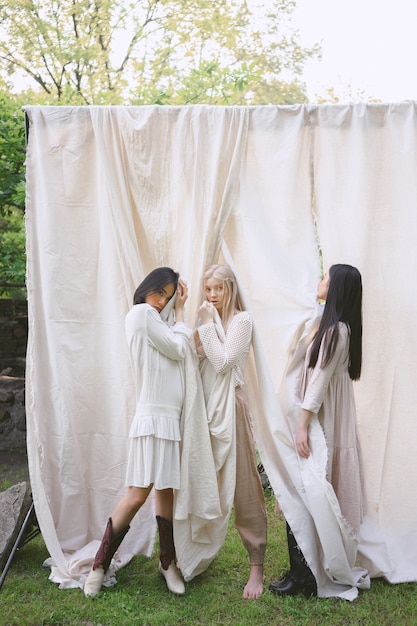 Mujeres hermosas que se colocan en el vestido blanco en jardín.