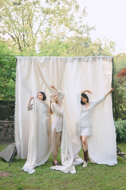 Mujeres hermosas que se colocan en el vestido blanco en jardín.