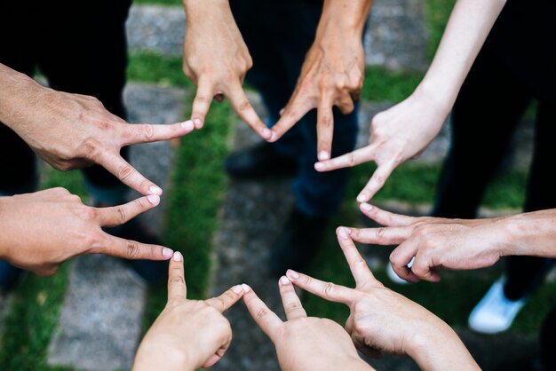 Mujeres y hombres amigos hacen forma de estrella con los dedos. El éxito, el concepto de amistad.