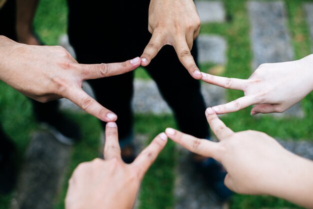 Mujeres y hombres amigos hacen forma de estrella con los dedos. El éxito, el concepto de amistad.