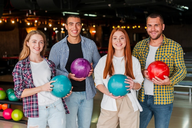 Mujeres y hombres con coloridas bolas de boliche tiro medio