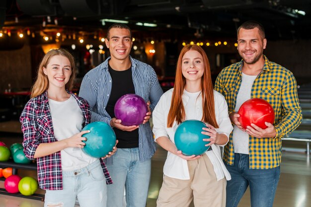 Mujeres y hombres con coloridas bolas de boliche tiro medio