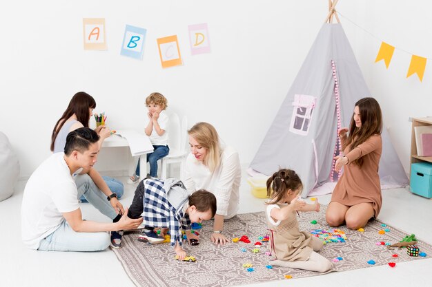 Mujeres y hombres jugando con niños en casa