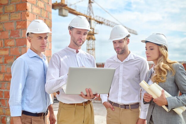 Mujeres y hombres mirando portátil en construcción