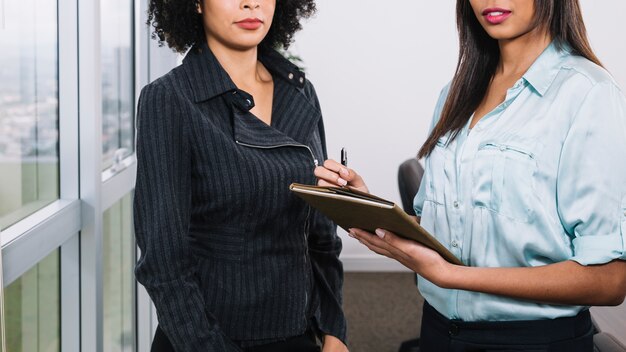 Mujeres jóvenes afroamericanas con documentos cerca de la ventana