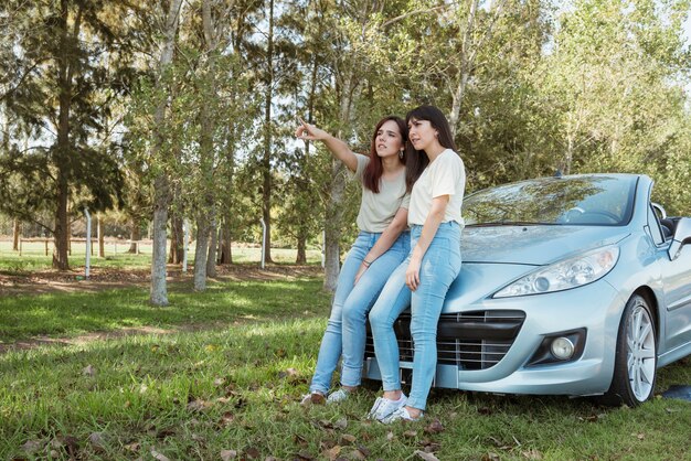 Mujeres jóvenes apoyadas contra su coche