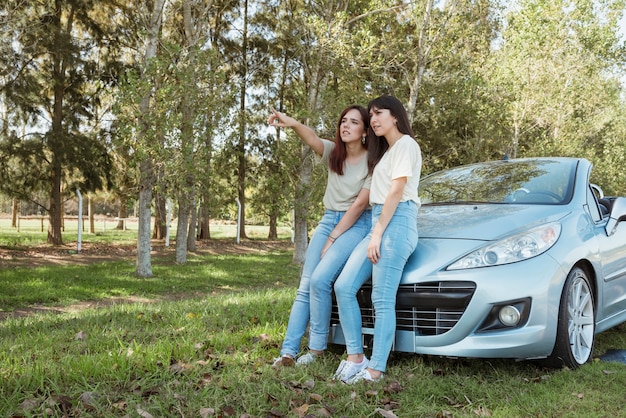 Mujeres jóvenes apoyadas contra su coche