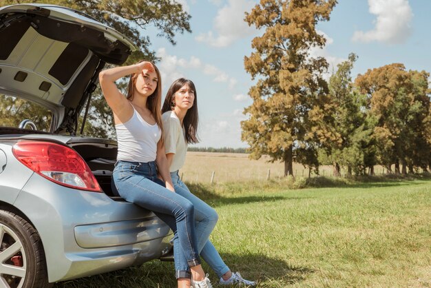 Mujeres jóvenes apoyadas contra su coche