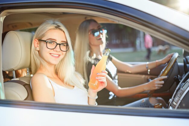 Las mujeres jóvenes en el auto sonriendo