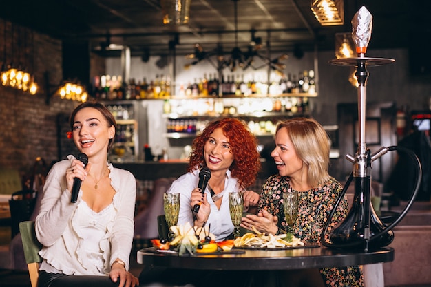 Mujeres jóvenes en un bar cantando karaoke