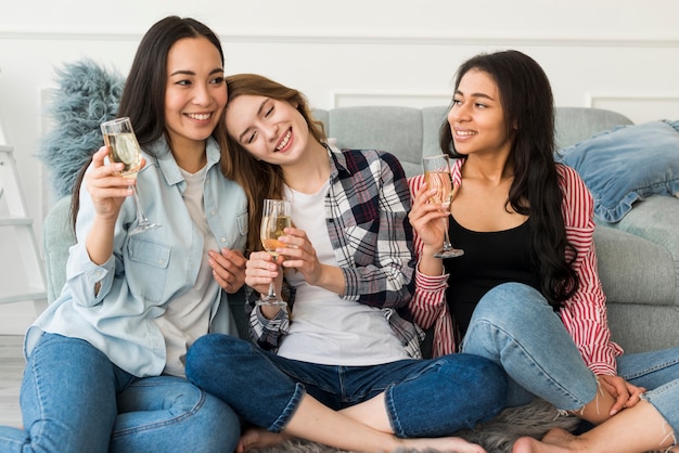 Mujeres jóvenes bebiendo champán en casa
