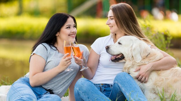 Mujeres jóvenes bebiendo junto a un perro