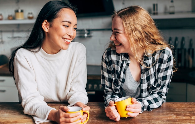 Mujeres jóvenes bebiendo té y sonriendo