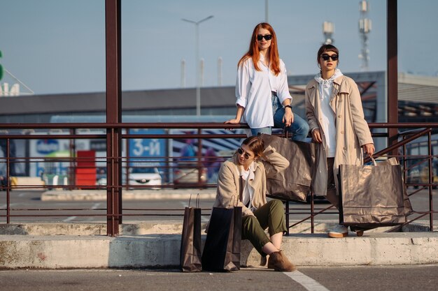 Mujeres jóvenes con bolsas de la compra en una parada de autobús