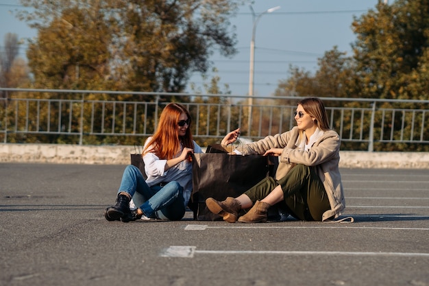 Mujeres jóvenes, con, bolsas de compras, sentado, en, estacionamiento