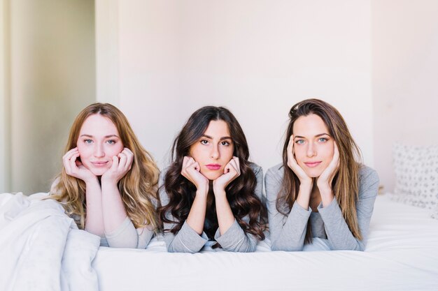 Mujeres jóvenes en la cama mirando a la cámara