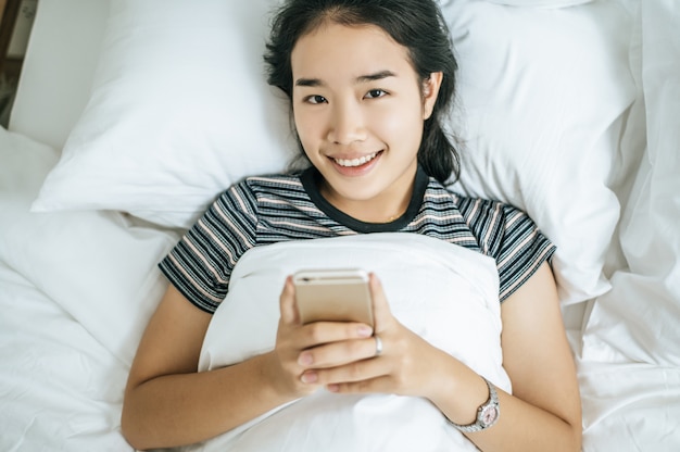 Mujeres jóvenes con camisas de rayas jugando teléfonos inteligentes