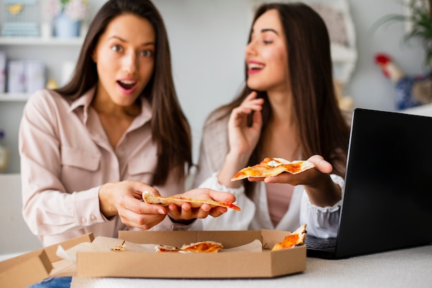 Mujeres jóvenes comiendo pizza después del trabajo