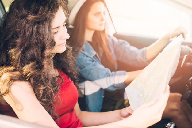 Mujeres jóvenes conduciendo coche con mapa