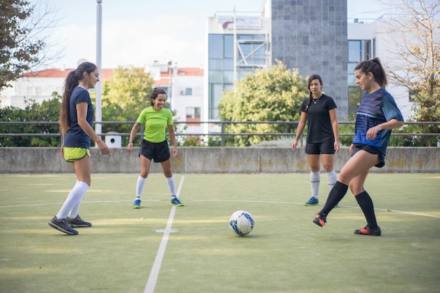Mujeres jóvenes deportivas entrenando en el campo de fútbol. Deportistas con coloridos uniformes parados en círculo, pateando pelotas, calentándose. Deporte, ocio, concepto de estilo de vida activo.