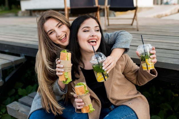 Mujeres jóvenes disfrutando de bocadillos y cócteles al aire libre