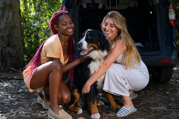 Mujeres jóvenes divirtiéndose con un perro en la playa