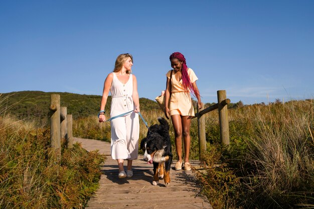 Mujeres jóvenes divirtiéndose con un perro en la playa