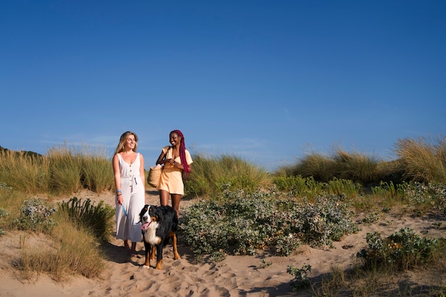 Mujeres jóvenes divirtiéndose con un perro en la playa