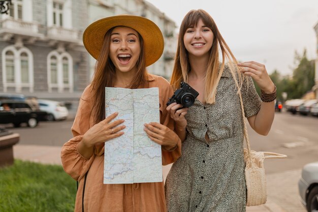 Mujeres jóvenes con estilo que viajan juntas en Europa vestidas con vestidos y accesorios de moda de primavera