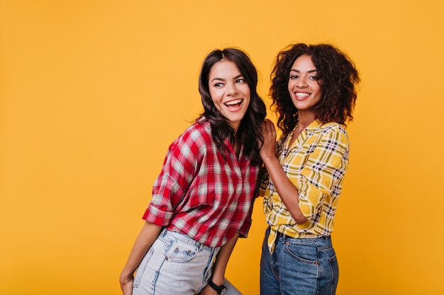 Mujeres jóvenes felices bailando. Retrato interior de dos chicas con estilo en jeans.