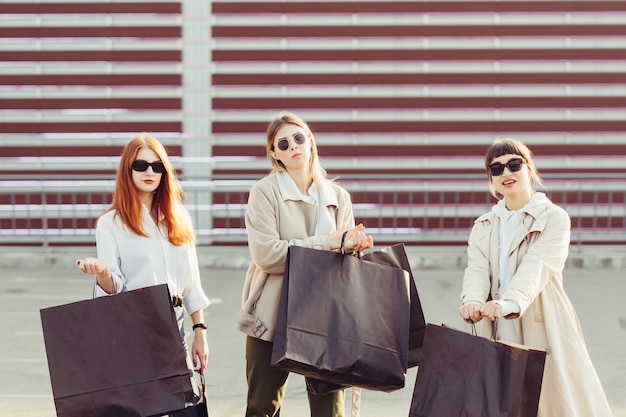 Mujeres jóvenes felices con bolsas de compras caminando en la calle.