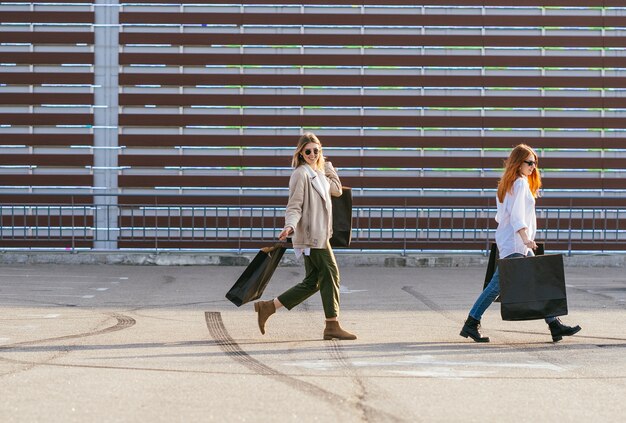 Mujeres jóvenes felices con bolsas de compras caminando en la calle.