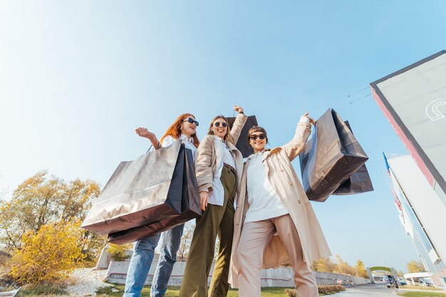 Mujeres jóvenes felices con bolsas de compras caminando en la calle.