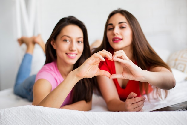 Mujeres jóvenes haciendo forma de corazón con manos