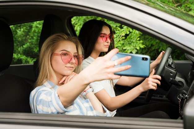 Mujeres jóvenes haciendo selfie en coche