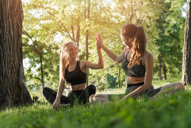 Mujeres jóvenes haciendo yoga en el parque