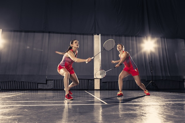 Mujeres jóvenes jugando bádminton en el gimnasio