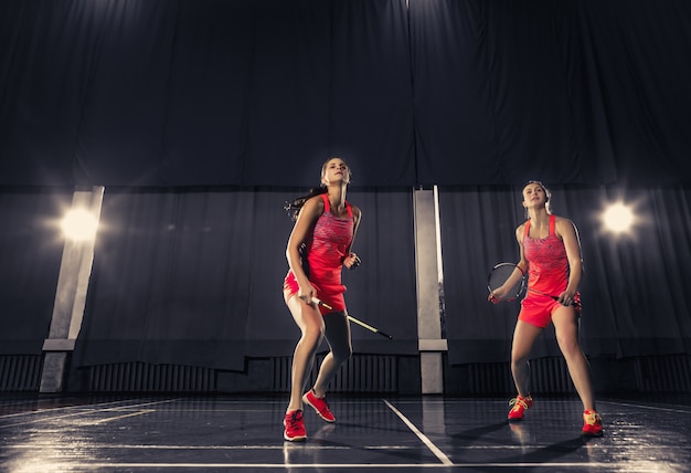 Mujeres jóvenes jugando bádminton en el gimnasio