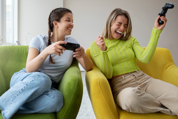 Foto gratuita mujeres jóvenes jugando videojuegos juntas