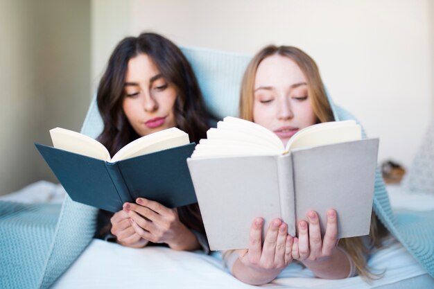 Mujeres jóvenes leyendo en la cama
