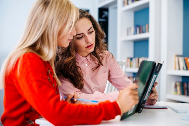 Mujeres jóvenes leyendo libros de texto juntos