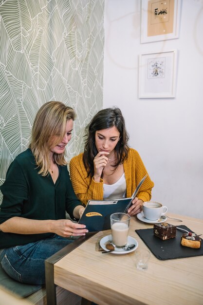 Mujeres jóvenes leyendo el menú en la cafetería