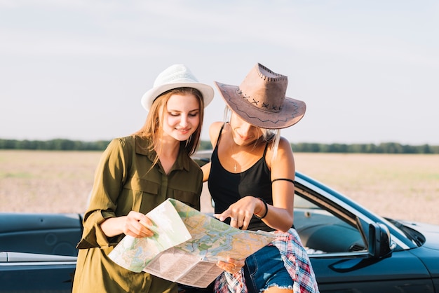 Mujeres jóvenes con mapa cerca de cabriolet