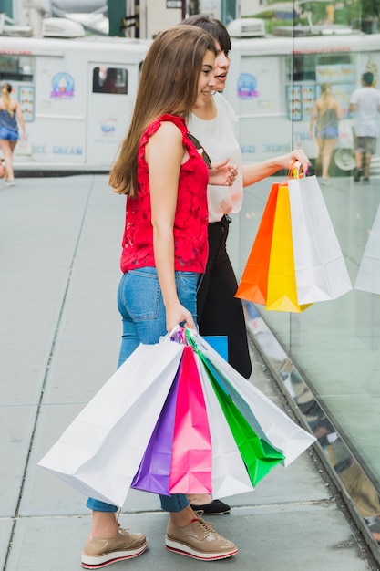 Foto gratuita mujeres jóvenes mirando la ventana de la tienda