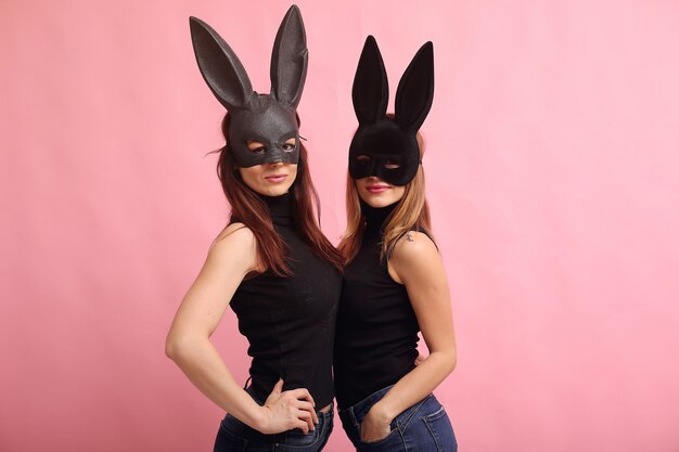 Mujeres jóvenes de moda posando con máscara de conejo negro